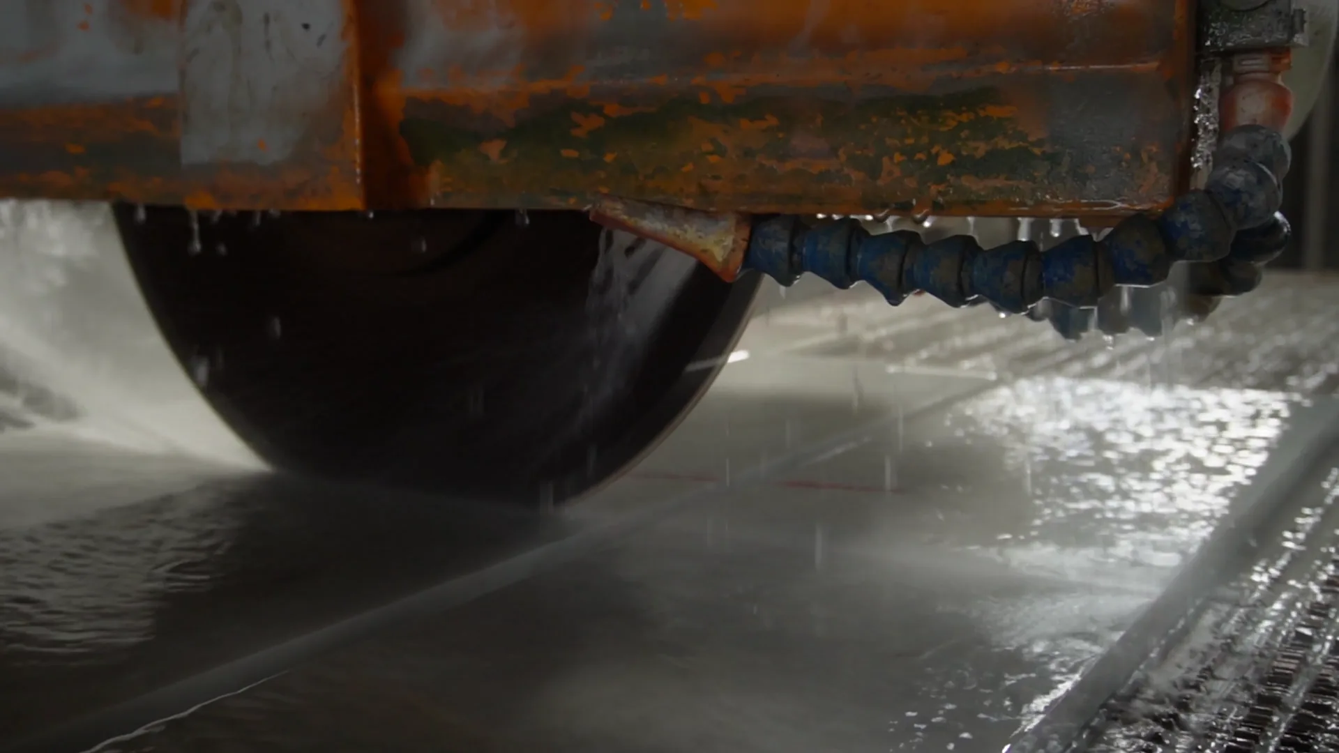 Large industrial saw cutting a natural stone slab with cooling water